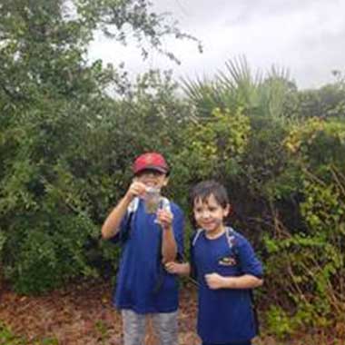 2 small boys holding up a coin.