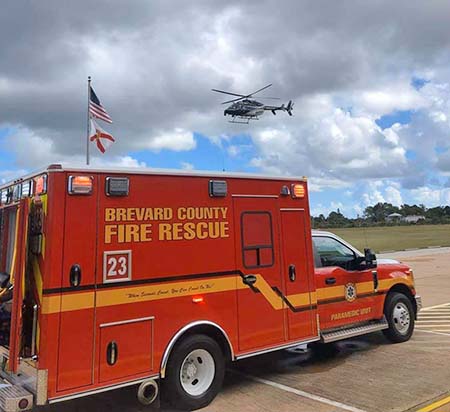 Brevard County Fire Rescue Paramedic Unit truck in foreground with helicopter flying overhead.