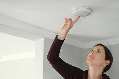 Woman checking a fire alarm.