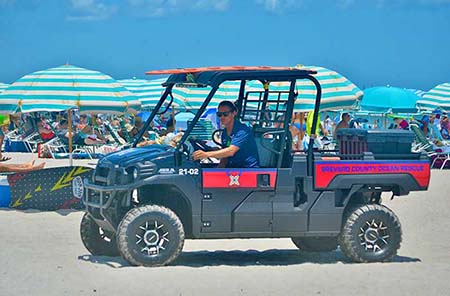 Patrolling the Beach An Ocean Rescue lifeguard driving all-terrain vehicle patrolling the beach in Cocoa Beach.