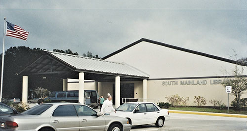 Current South Mainland Library entrance, with cars and people in the parking lot.