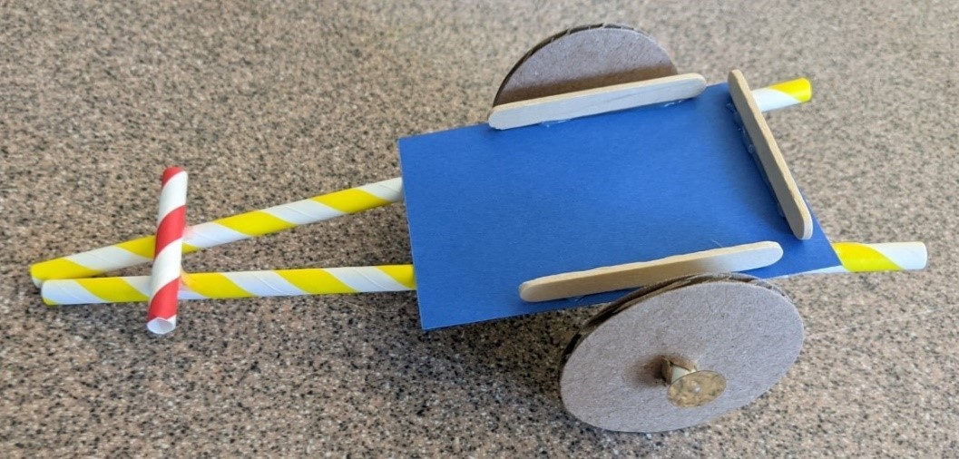 Toy cart with cardboard wheels and a frame made of a paper base, straws, and craft sticks.