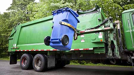 Garbage truck picking up a collection bin.