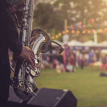 Saxophone player performing to a crowd at a festival.